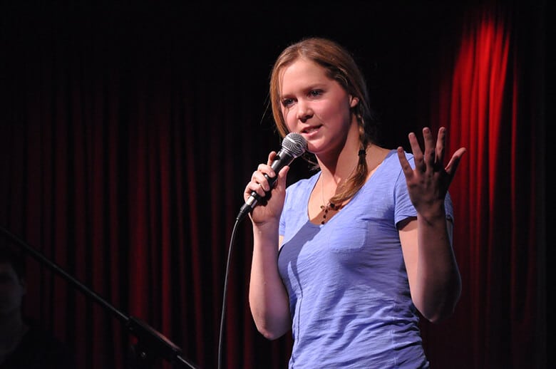 A woman in a blue shirt is holding a microphone at the North Shore Animal League event.