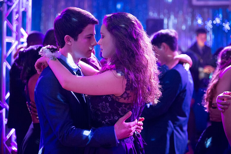 A young man and woman hugging at a party while watching Netflix.