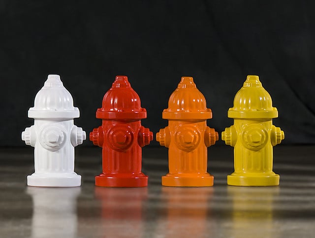 Four different colored fire hydrants are lined up on a table, ready for any potential canine mishaps.