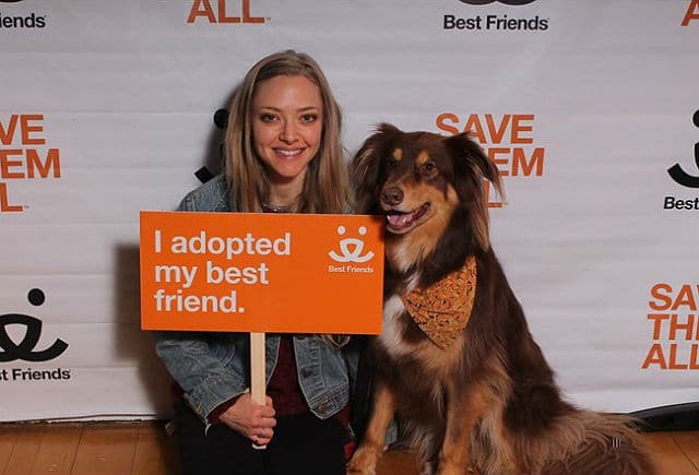 A woman holding a sign that says I adopted my best friend from Best Friends Animal Society.