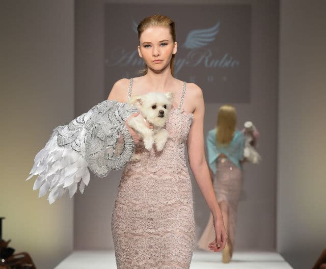 A model walks down the runway with a dog in her arms, showcasing the unique vision of designer Anthony Rubio.