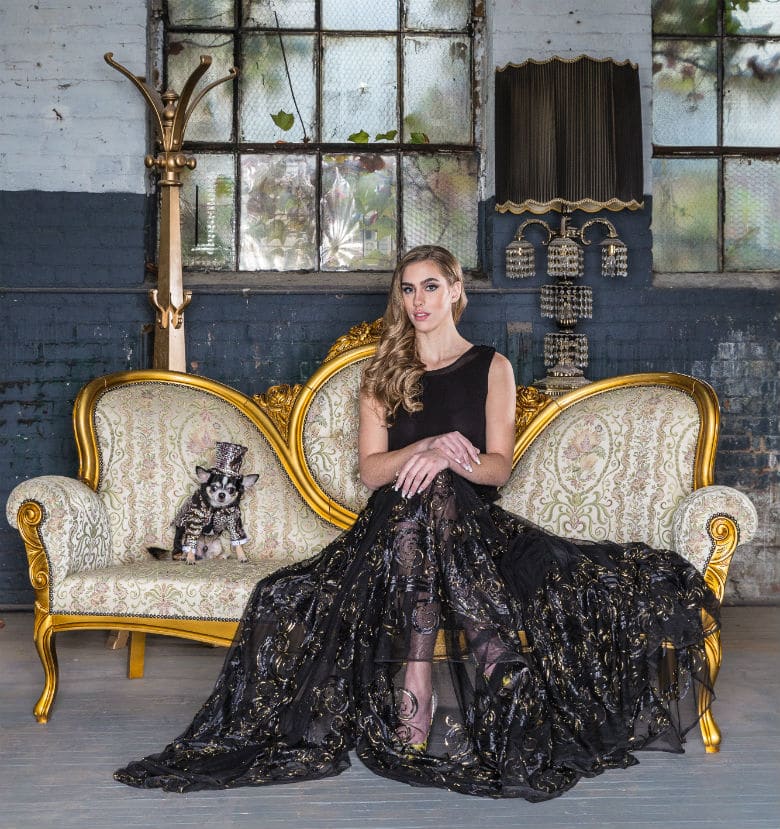 A woman in a black dress sitting on a gold couch at a runway show.