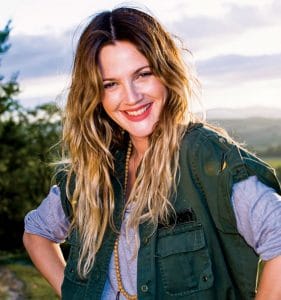 Drew Barrymore, a woman with long blonde hair, smiling at ASPCA's Bergh Ball in a green jacket.