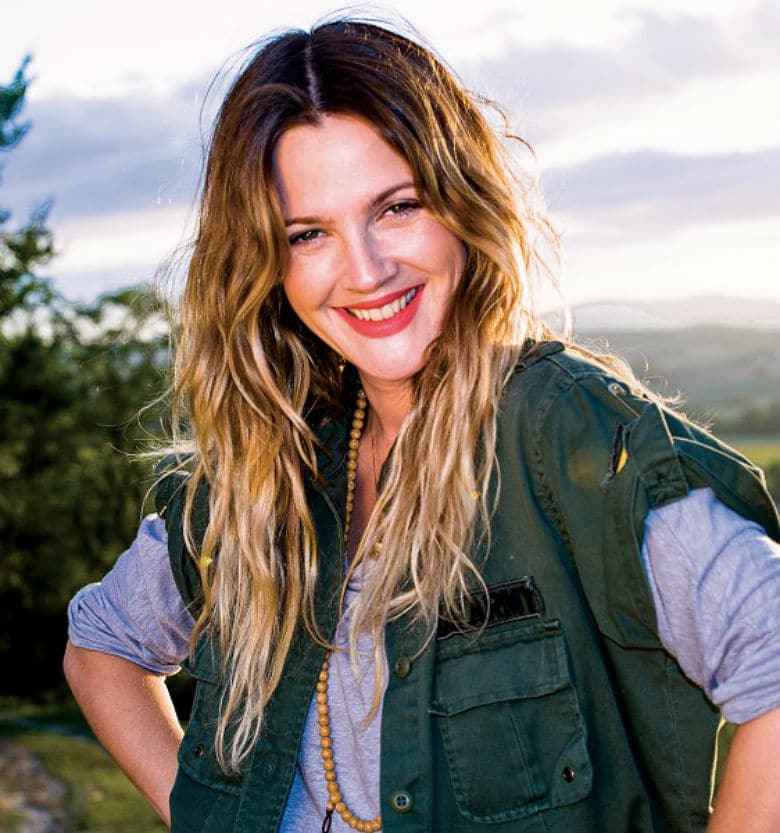 Drew Barrymore, honored guest at ASPCA's Bergh Ball, smiling in a green jacket with her long blonde hair.