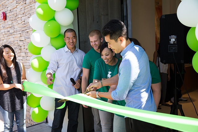 A group of people cutting a ribbon in front of a Healthy Spot.