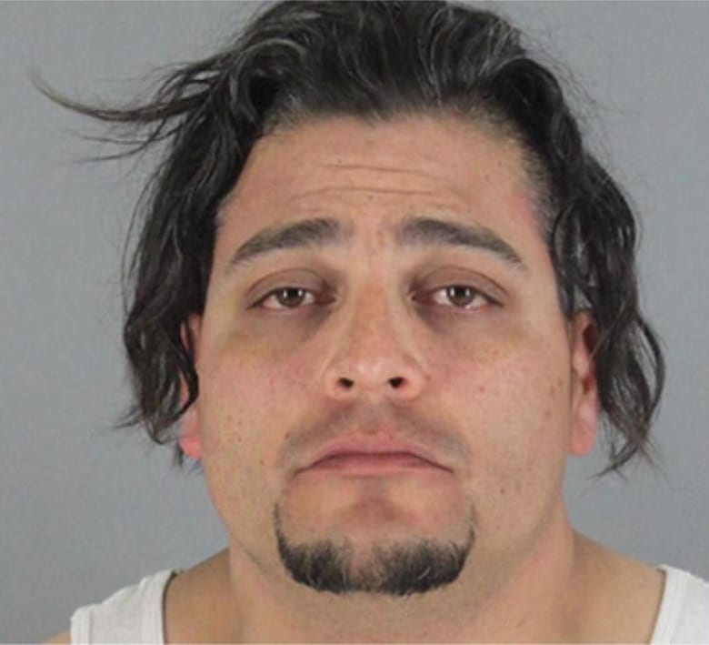 A mugshot of a man with long hair suspected of animal cruelty.