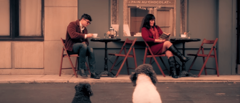 A man and woman, joined by their beloved canine companion, sitting at a table.