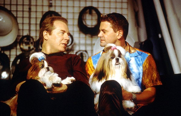 Two men sitting on a couch with two shih tzu dogs, exemplifying the affection between dog lovers.