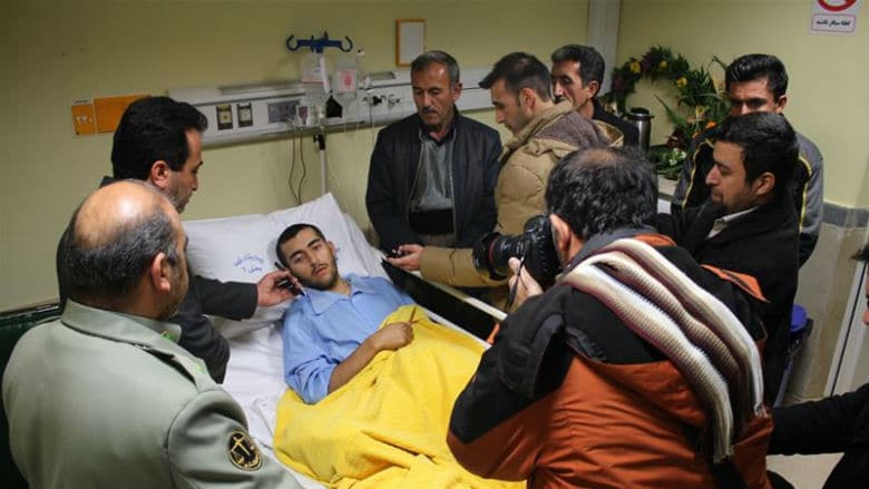 A man in a hospital bed, hailed as a national hero, is surrounded by reporters.