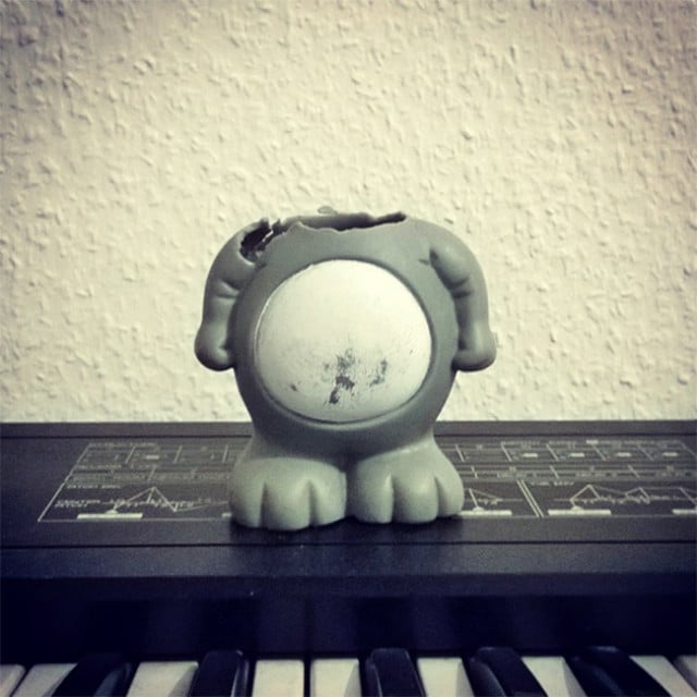 A small figurine sits on top of a chewed piano.