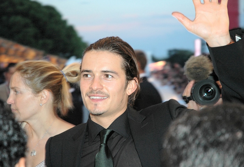 Orlando Bloom, the man in a suit and tie, waves to the crowd.