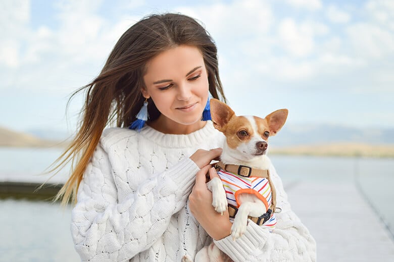 A woman showing some love to a dog on a dock.