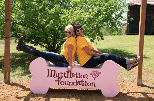 Miranda Lambert Gives $200 to Two people posing in front of a pink dog shaped bench.