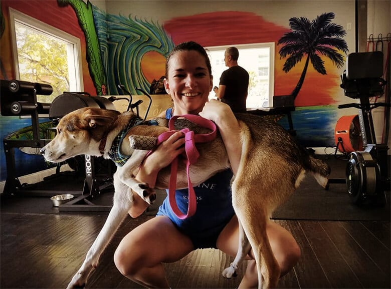 A woman performing SquatYourDog exercise in a gym.