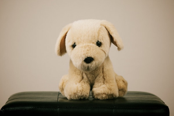 A fake dog sitting on a black chair.