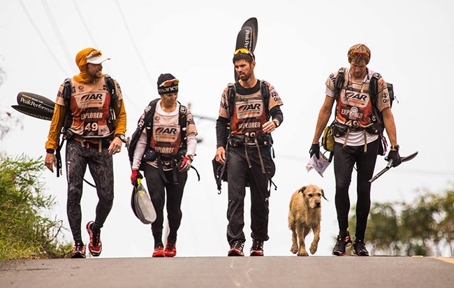 A group of people with backpacks and dogs found in the amazon jungle, walking down a road.