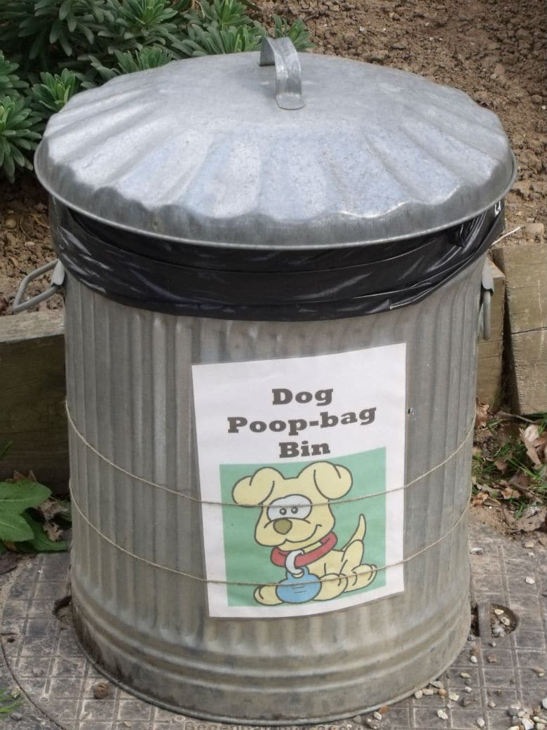 A composting trash can with a sign that says dog poop bag in San Francisco.