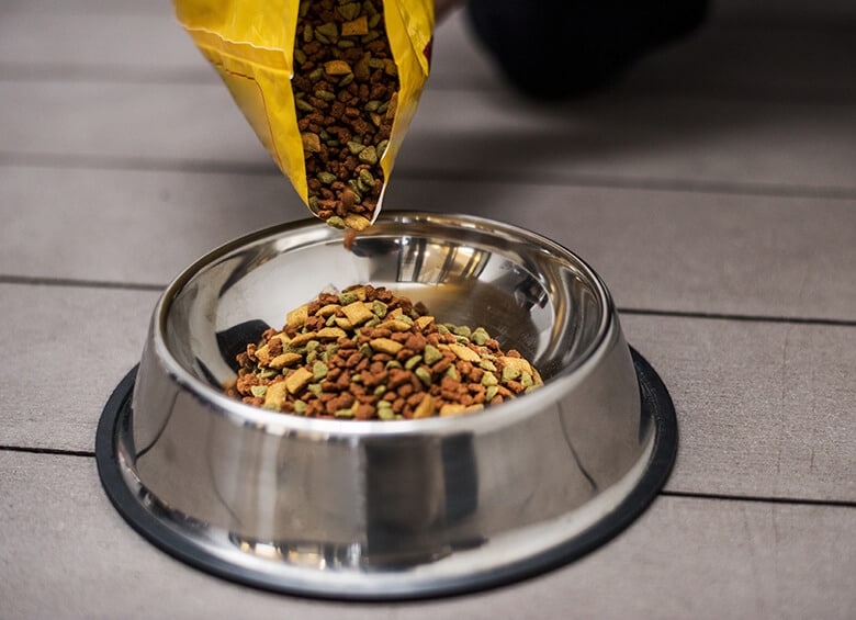 A person pouring recalled dog food from various brands into a bowl.