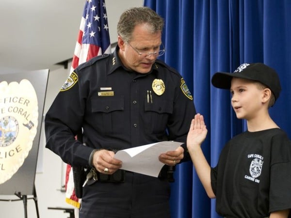 Zachary Boucher, a young boy, is being sworn in by a police officer.