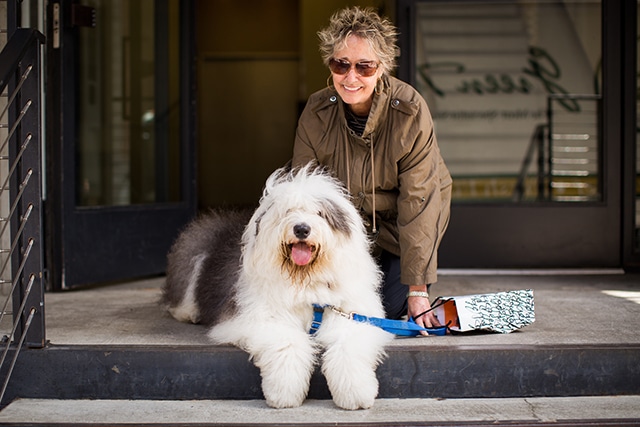 A dog owner with her furry companion on the steps of a building in New York City.