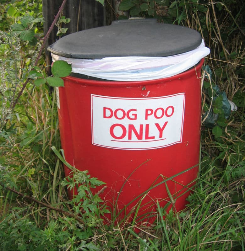 A red bucket with a sign that says dog poop only in Brooklyn Park as part of a new program.