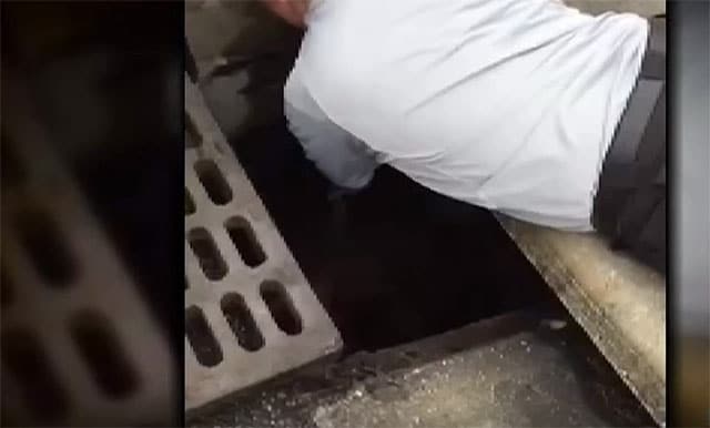 Caught on video, a daring rescue unfolds as a man lays on the ground in front of a drain.