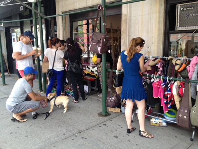 A group of people standing in front of a store in downtown.