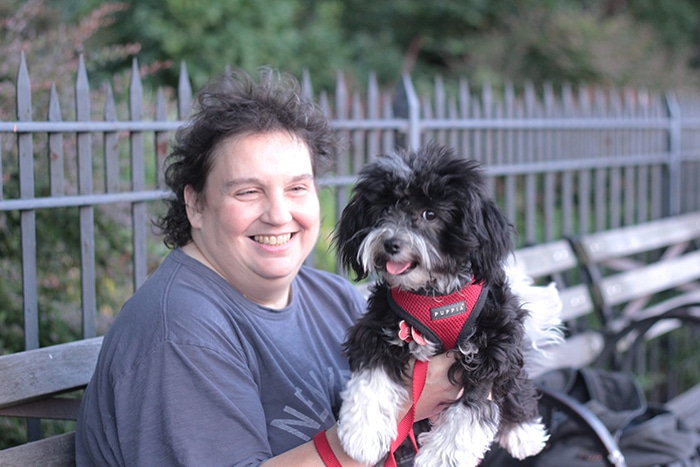 A woman holding a black and white dog she found on the street.