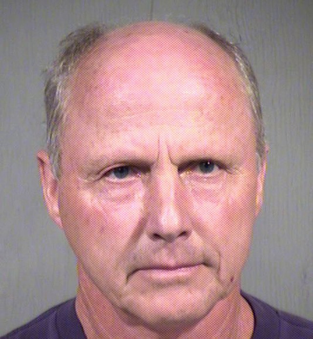 A mugshot of a man in a purple shirt.