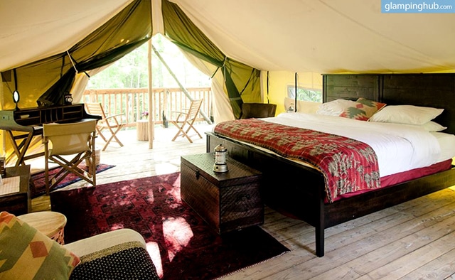 A glamping tent with a bed and a bedside table.