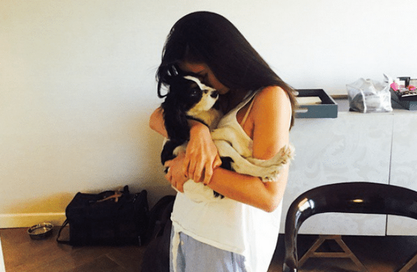 Olivia Munn is holding a dog in her arms.