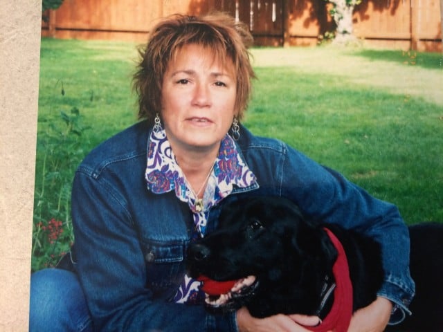 Leslee Kirkendall walking her black dog in the grass.