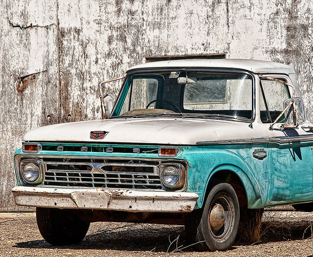 A vintage pickup truck parked in front of a brick wall.