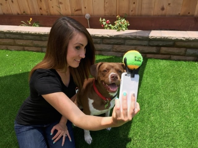 A woman capturing a poochie selfie with her dog and a tennis ball.