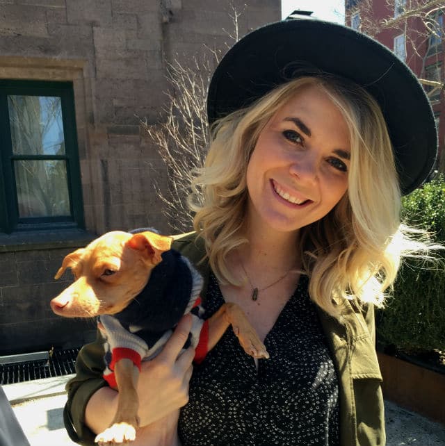 A woman in a black hat holding a chihuahua at a pup-up shop.