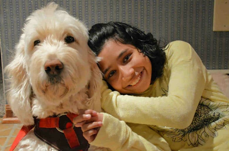 A disabled girl accompanied by a Service Dog Wonder, both wearing a white harness.