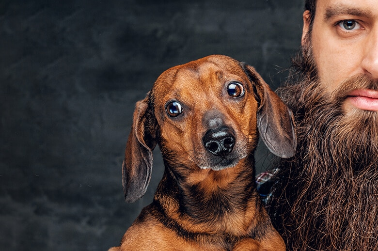 A bearded man embracing his furry companion.