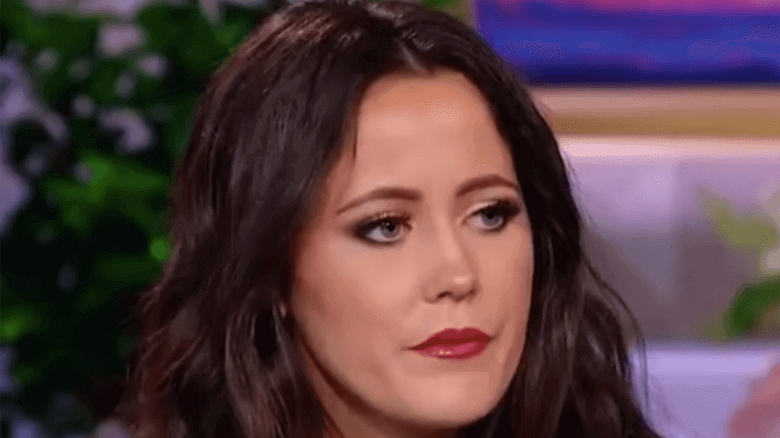 A woman with long dark hair is sitting on an interview.