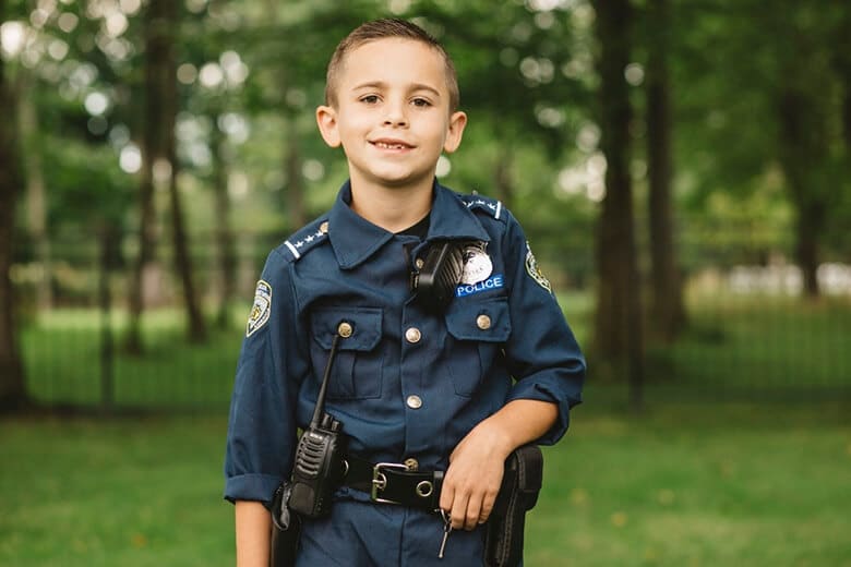 A 9-year-old boy in a police uniform posing for a photo, advocating to protect K-9 dogs and provide free bulletproof vests.