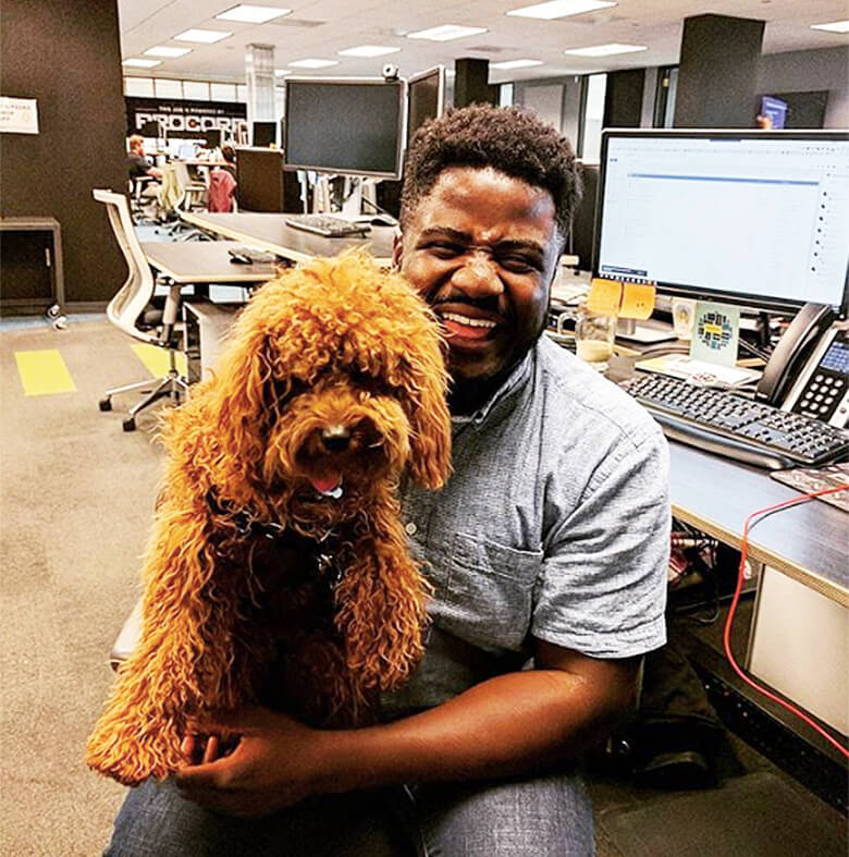 A man holding a dog in a dog-friendly office.