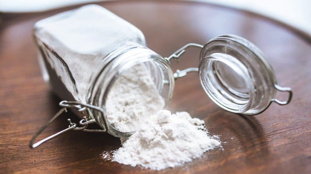 White powder in a glass jar on a wooden table.