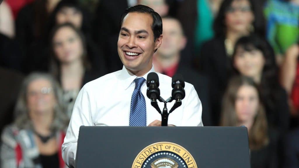 A man smiling at a podium in front of a crowd.