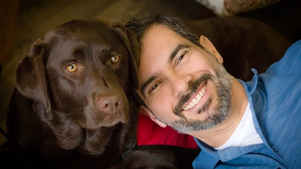 A man with a brown labrador dog posing for a photo.