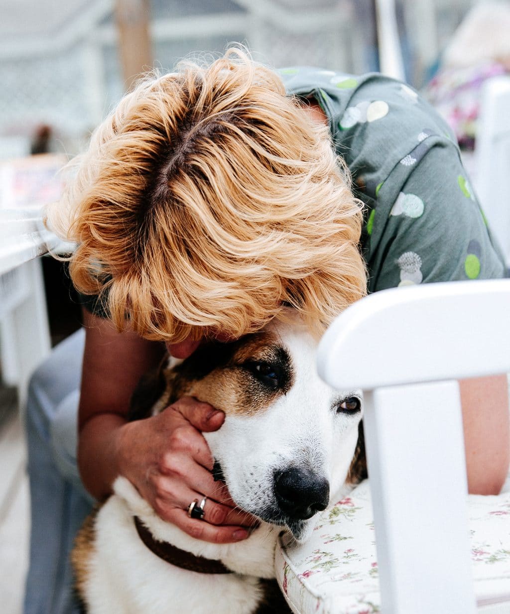 A woman hugs her dog, which she ended up adopting, while sitting on a chair.