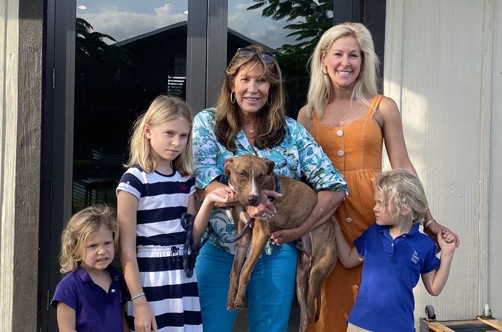 A woman and her children are posing for a picture with their miracle dog, found in the aftermath of Hurricane Rubble.