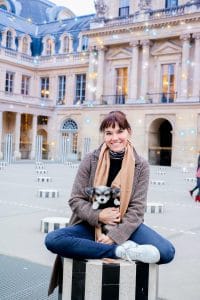 A woman holding a dog in front of a building to celebrate Love Your Pet Day.