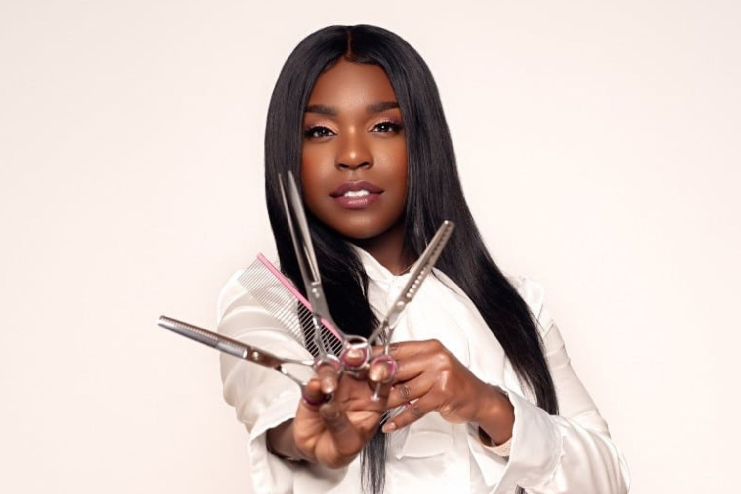 A black woman, a Grooming Extraordinaire, holding a pair of scissors.