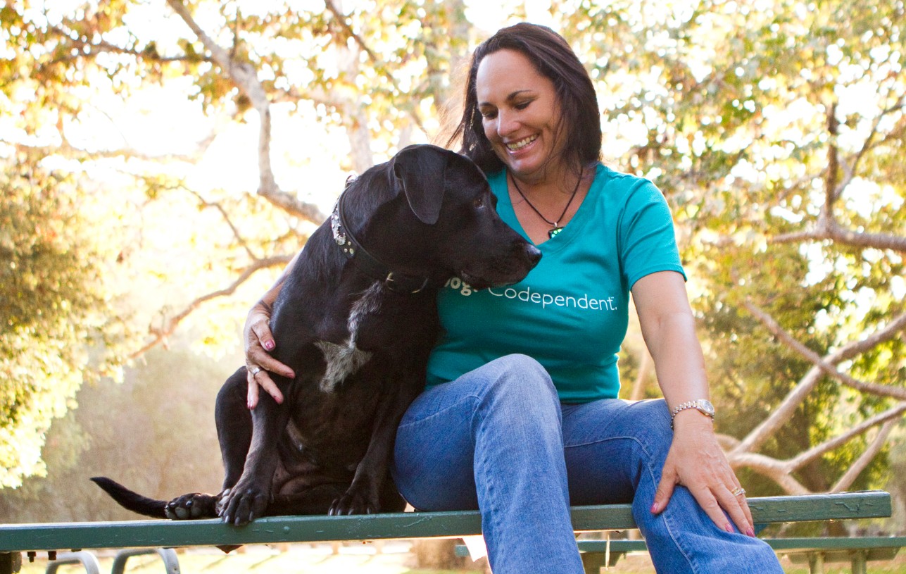 A woman sitting on a bench with a black dog rescued from a wildfire.