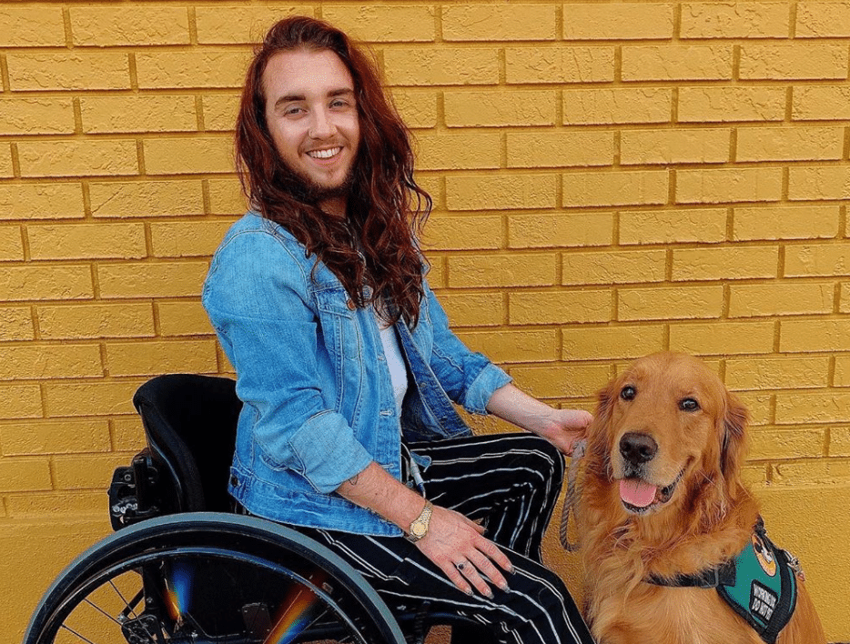 A disabled man in a wheelchair with his service dog, a golden retriever.