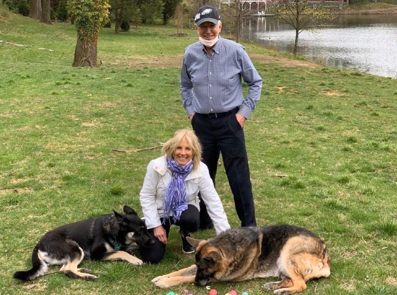 A man and woman posing with their shelter dogs in a park.